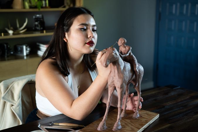 Cool young biracial woman creating sculpture with clay