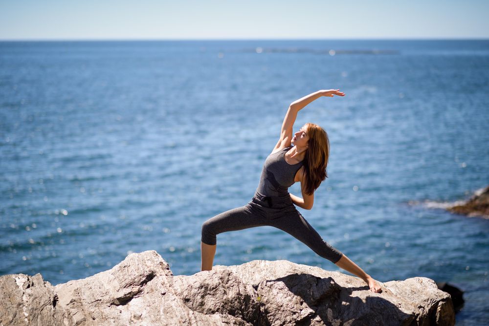 Young woman doing yoga on a rocky beach