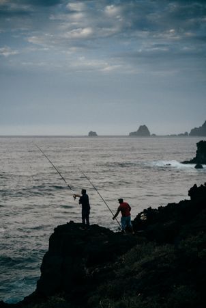 Two men fishing at dusk in the Canary Islands
