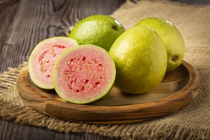Fresh sliced guavas on wooden table.