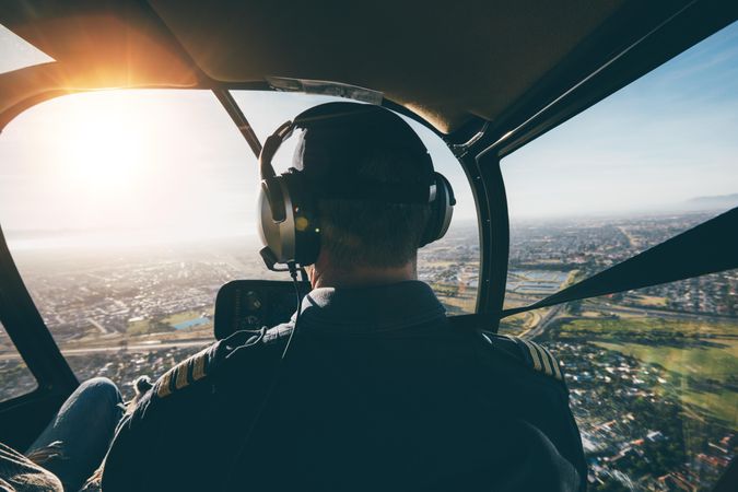 Back shot of a male in headphones flying a helicopter