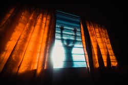 Shadow of person leaning on a window in a dark room