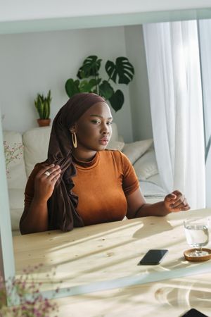 Beautiful Black woman in hijab looking in mirror