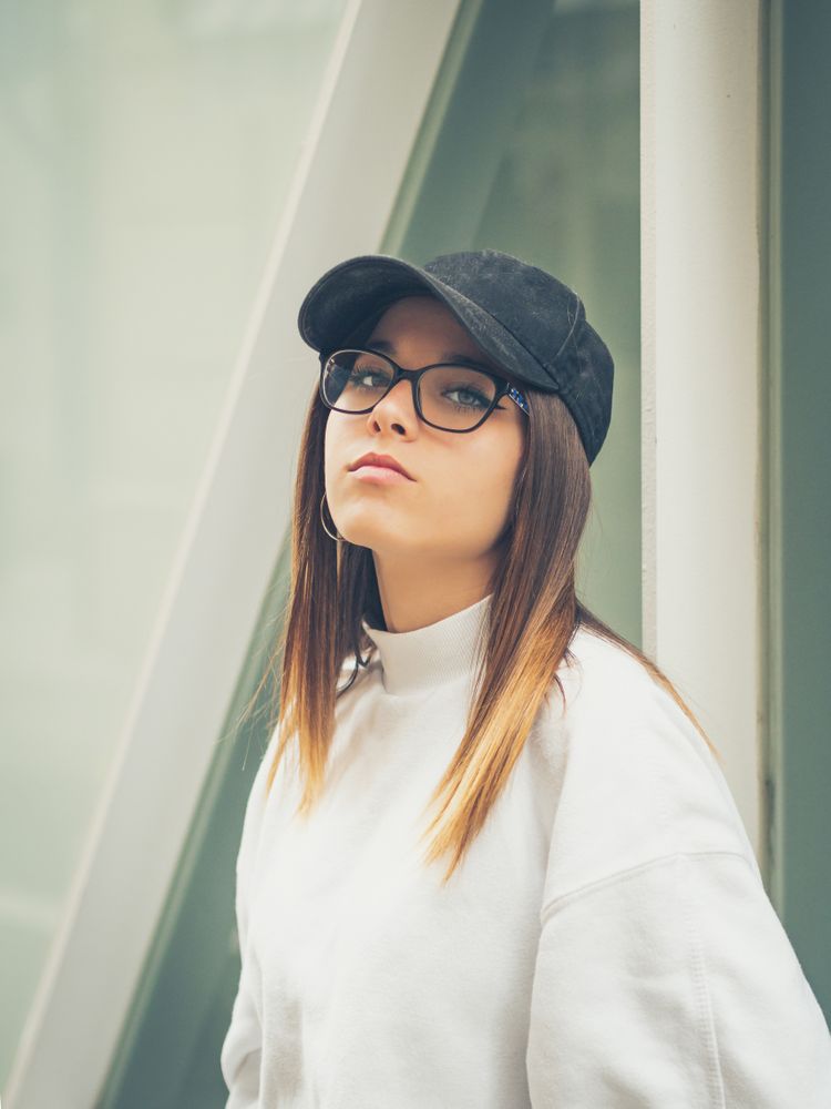 Young woman with glasses standing against wall
