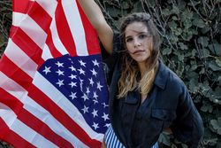 Young woman in casual clothing and American ensign enjoying in nature