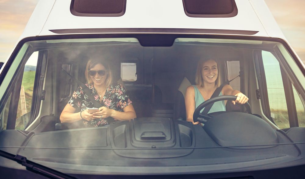 Woman driving a motorhome with her female friend in passenger seat
