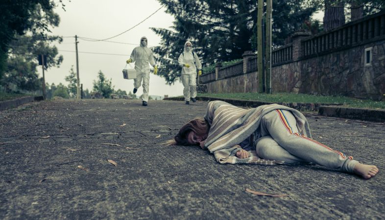 People in bacteriological protective suits running to help a woman