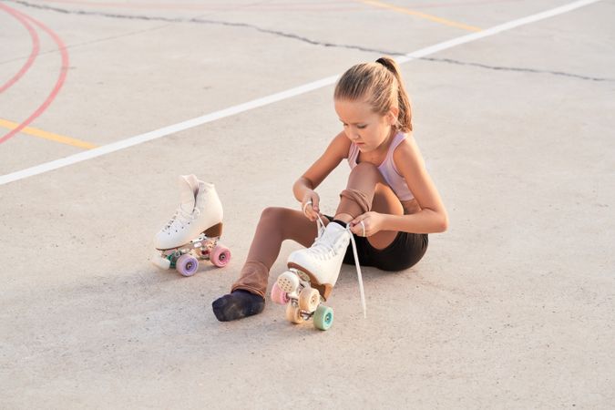 Girl putting on roller skate in city