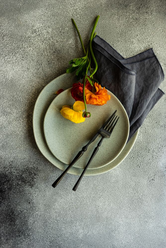 Top view of rustic table setting with ranunculus flowers on grey plate