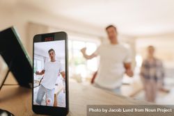Man dancing in front of a mobile phone with family at the back 4NZrr4