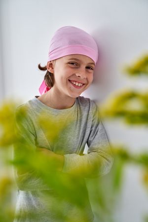 Smiling sick kid leaning on wall in clinic