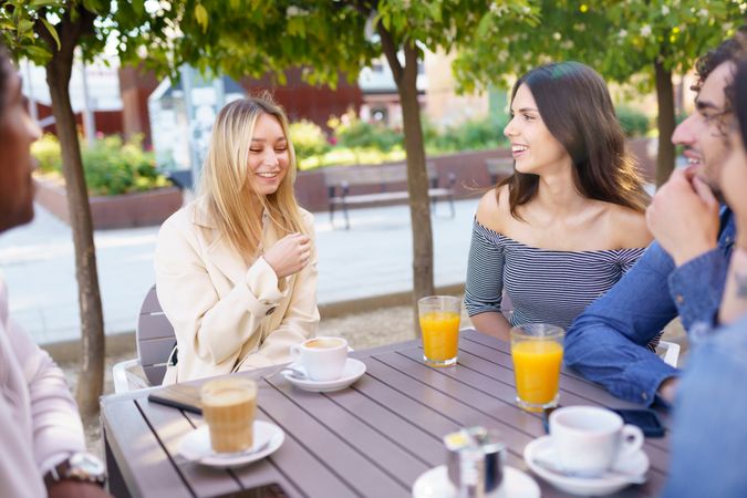 Multi-ethnic group having a conversation over coffee and juice at outside table
