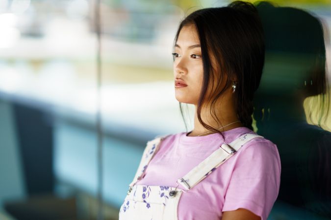 Female in pink t-shirt leaning on reflective wall