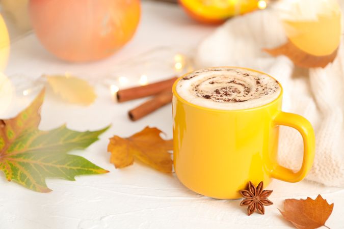 Composition with cup of pumpkin latte on light background