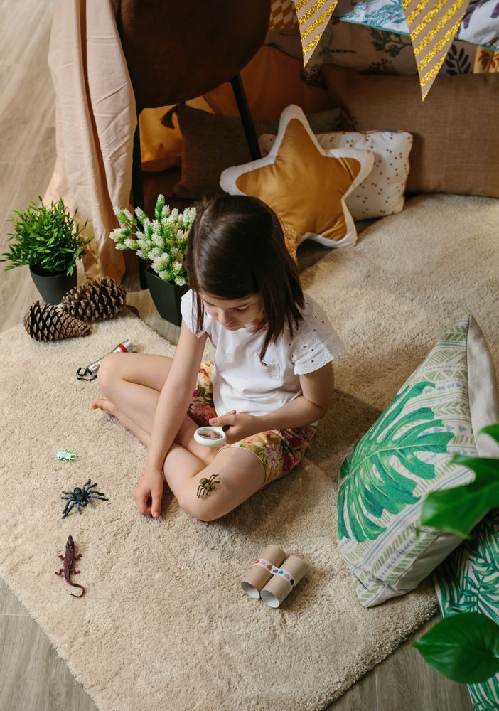 Girl playing observing toy bugs with a magnifying glass