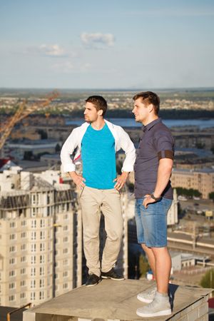 Two men stand enjoying view onto of roof