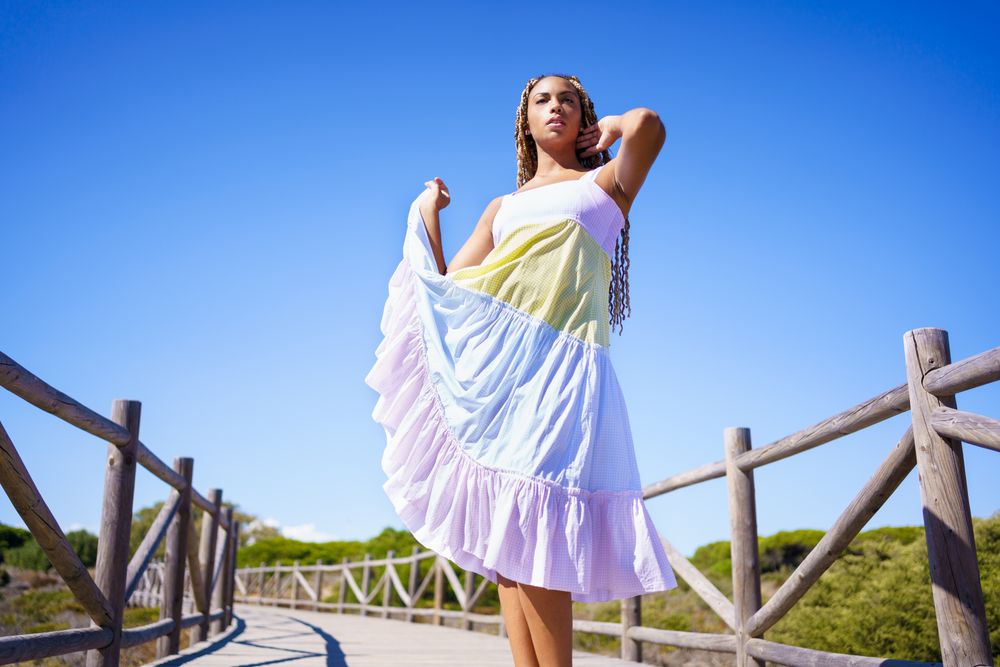 Elegant female playing with colorful dress on clear day