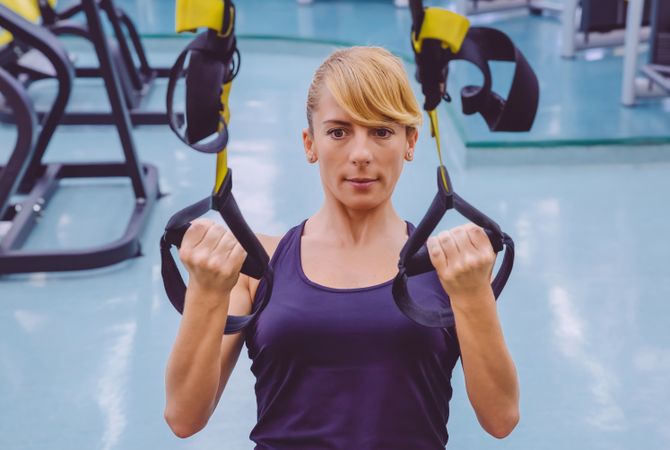 Fit woman doing upper body exercise with suspension ropes