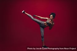 Black female fighter practicing high kick in studio bE11nb