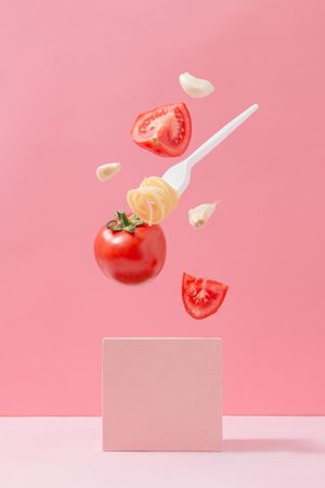 Pasta ingredients in free fall on pink background with fork