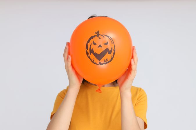 Concept of Halloween, Woman holds Halloween balloon on light background