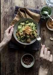 Hands taking pasta paccheri with kale pesto and nuts