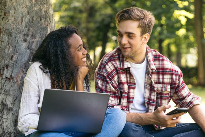 Multiracial couple studying in the park with laptop