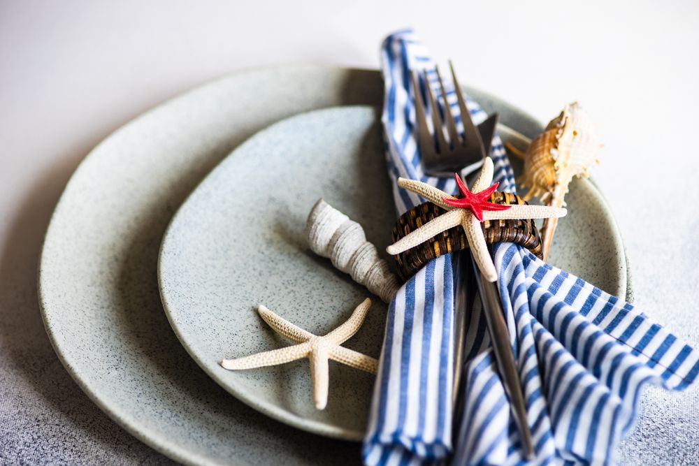 Marine table setting with sea stars and shells with blue striped napkin