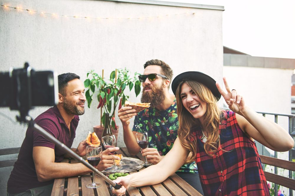 Fun group of friends eating outside and taking a selfie
