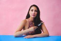 Hispanic woman with long brown hair holding up large make up brush