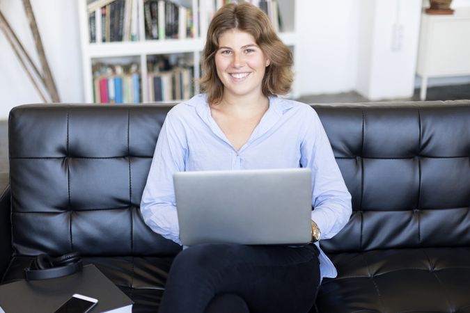 Content woman sitting on a sofa at home working on a laptop