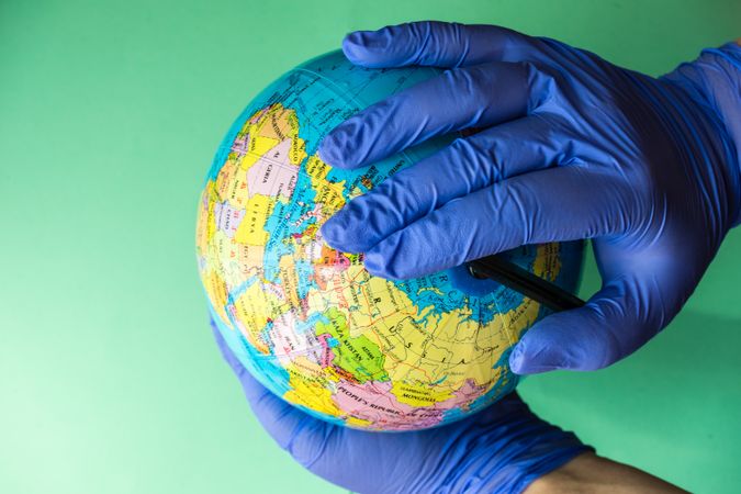 Hands in blue latex gloves holding globe