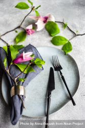 Plate & cutlery with magnolia flowers on grey table 0v3R3g