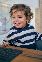 Cheerful boy with laptop at home