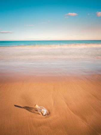 Bottle in sand near sea