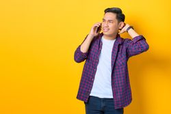 Asian male in argument on cell phone in yellow studio shoot