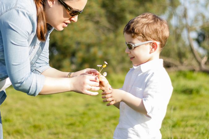 Son giving bouquet of flowers to mother in field