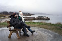 Tourists relaxing on bench on elevation by sea