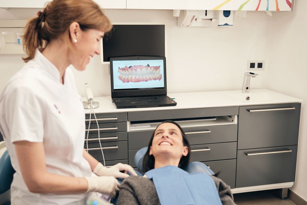 Happy stomatologist speaking with patient before treatment in dental clinic