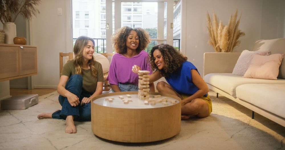 Group of Young Female Friends Playing a Physical Skill Blocks Game at Home in Cozy Sunny Living Room.