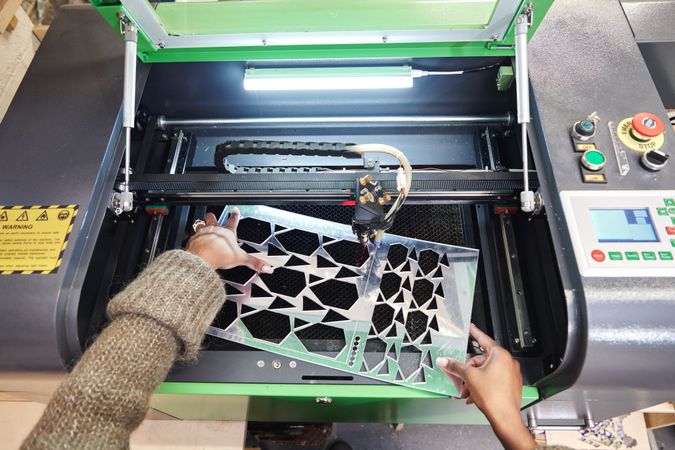 Woman removing material from laser cutter