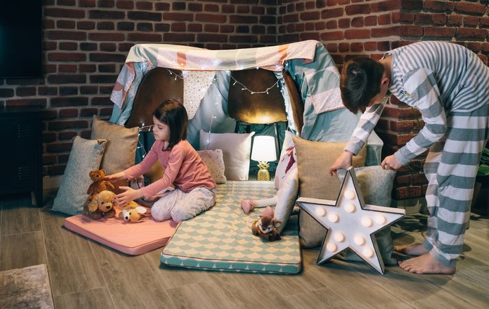Male teenager helping little sister prepare a diy tent