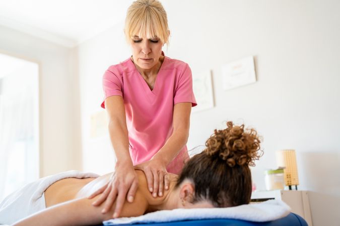 Female masseuse working on client's shoulders