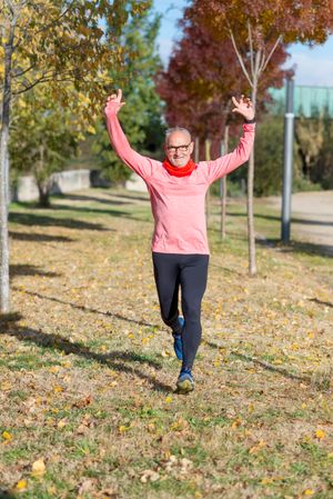 Happy older man running with arms above his head