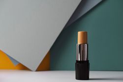 Concealer stick on modern background with geometric shapes.