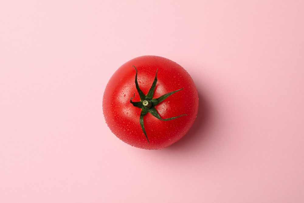 Fresh ripe tomato on pink background, top view