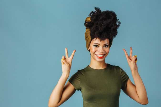 Studio shoot of Black woman smiling making the peace sign with both hands