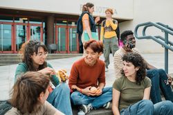 Diverse students resting on steps on street