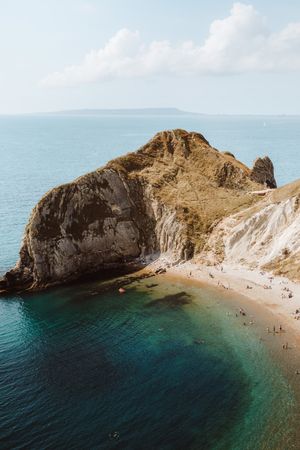 Sandy beach in bay by cliff