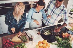 Top view looking down at friends cooking vegetables together